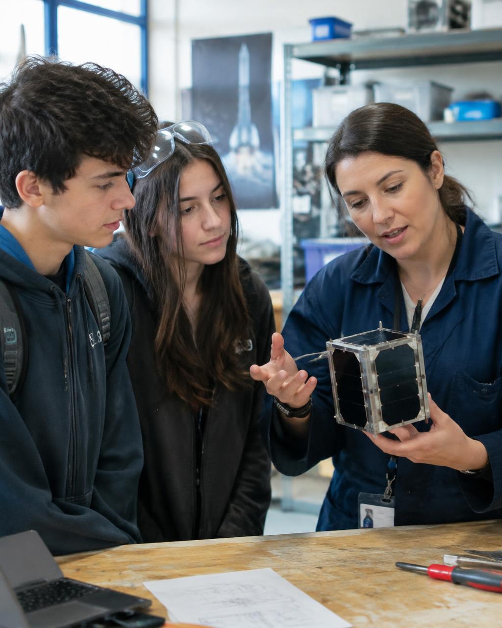 Une ingénieure présente un nanosatellite à deux lycéens